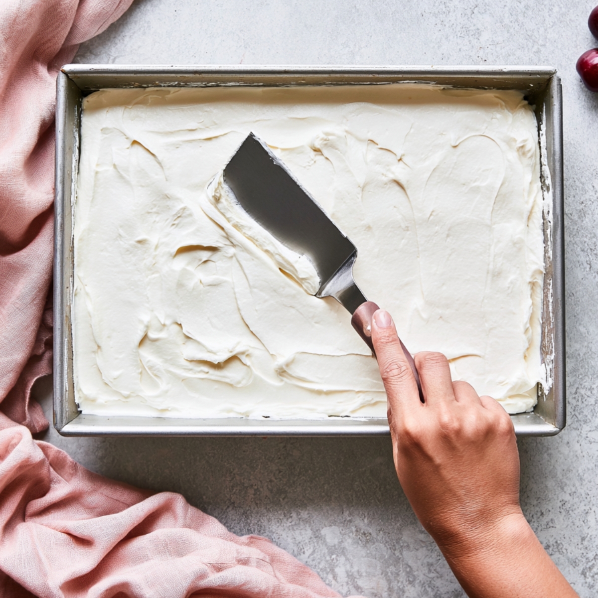 Easy Black Forest Icebox Cake Recipe 11 Spreading a smooth cream cheese layer evenly in a rectangular baking pan with an offset spatula for a no-bake cherry Oreo icebox cake.