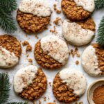 Soft Gingerbread Latte Cookies dipped in creamy vanilla latte glaze and dusted with cinnamon, arranged on parchment paper with evergreen sprigs.