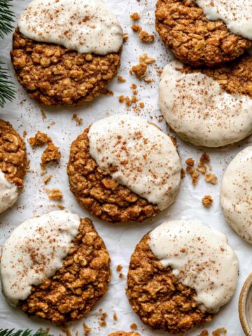 Easy Gingerbread Latte Cookies Recipe 2 Soft Gingerbread Latte Cookies dipped in creamy vanilla latte glaze and dusted with cinnamon, arranged on parchment paper with evergreen sprigs.