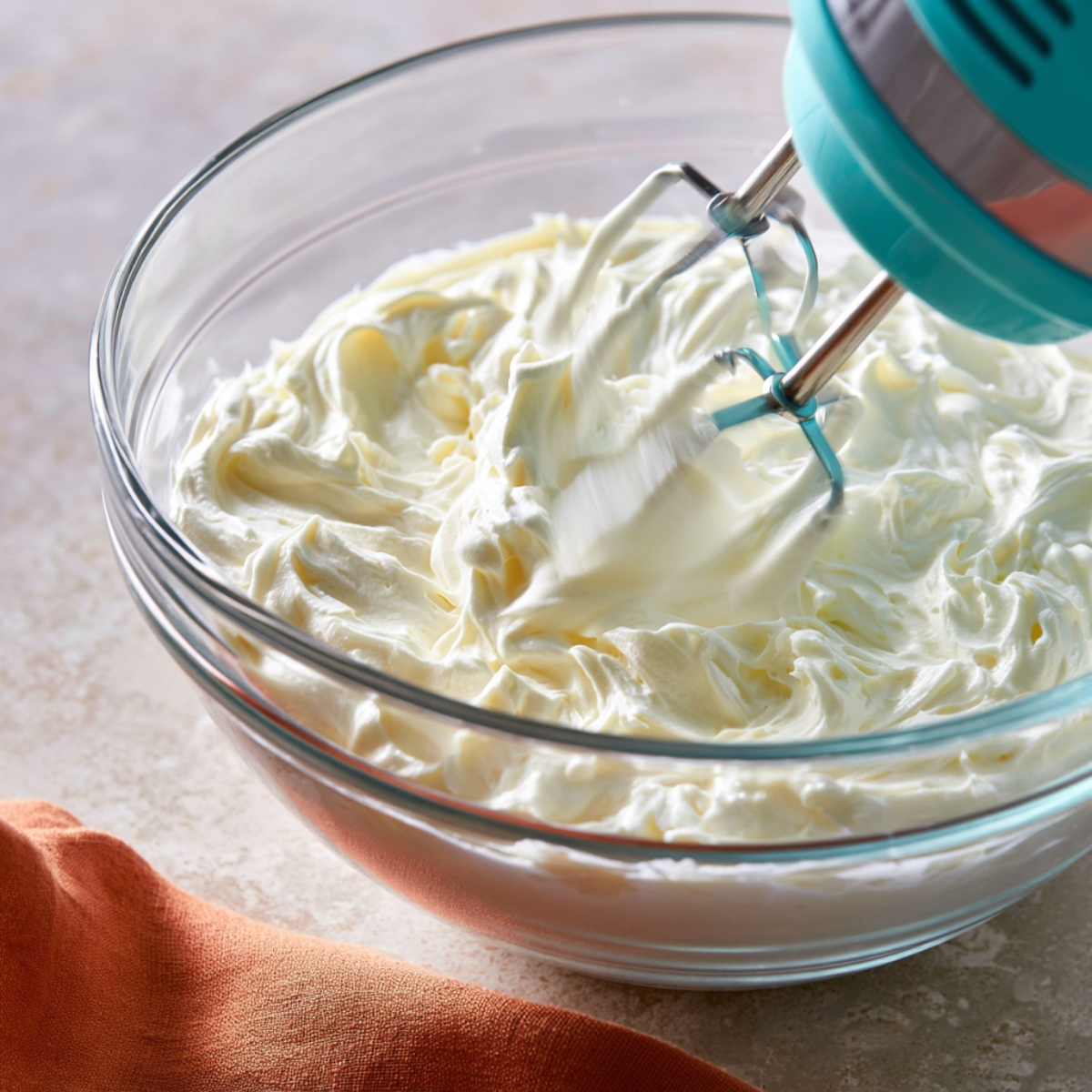 Easy Black Forest Icebox Cake Recipe 10 Hand mixer whipping a fluffy cream cheese filling in a glass bowl, creating a smooth and creamy mixture for a no-bake dessert.