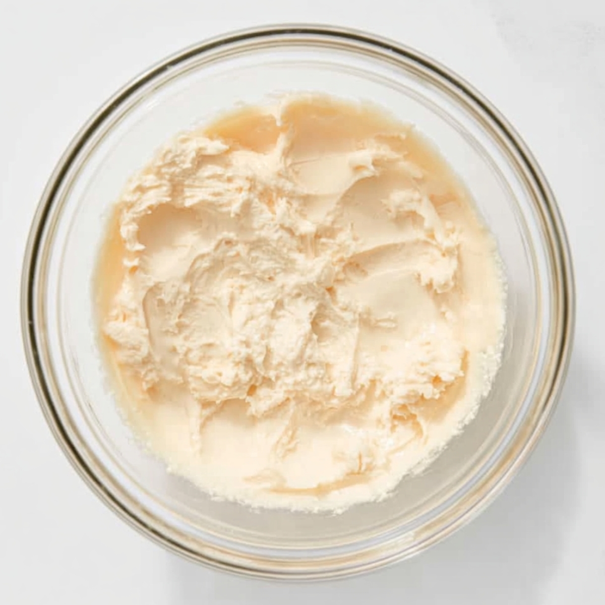 The Best Butterscotch Lush Recipe 11 Cream cheese mixture in a clear glass bowl, showing a smooth and fluffy texture prepared for the creamy layer of a no-bake butterscotch lush dessert.