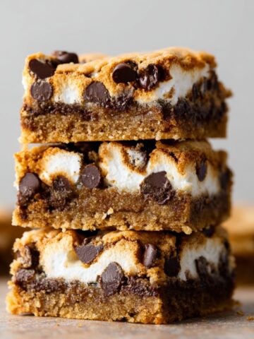 Easy S'mores Cookie Bars Recipe 2 Stacked S'mores Cookie Bars with gooey marshmallow filling, melted chocolate chips, and golden graham cookie layers, close-up dessert photography showcasing rich texture and indulgent homemade treats.