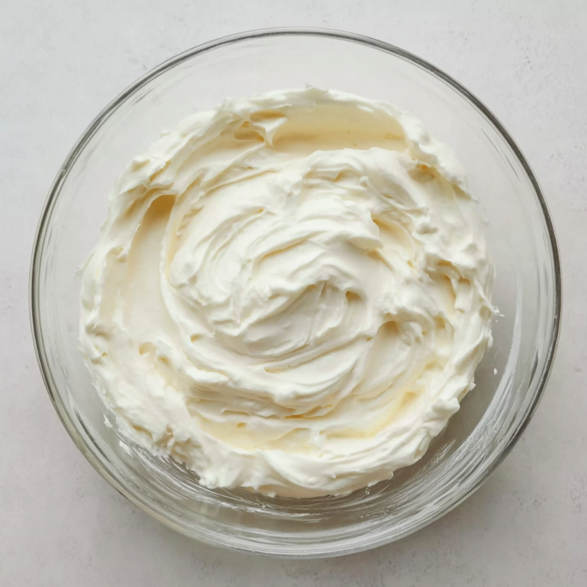 No-Bake Banana Cream Cheesecake 11 Smooth whipped cream and cream cheese mixture with soft peaks in a clear glass bowl, viewed from above on a light countertop.