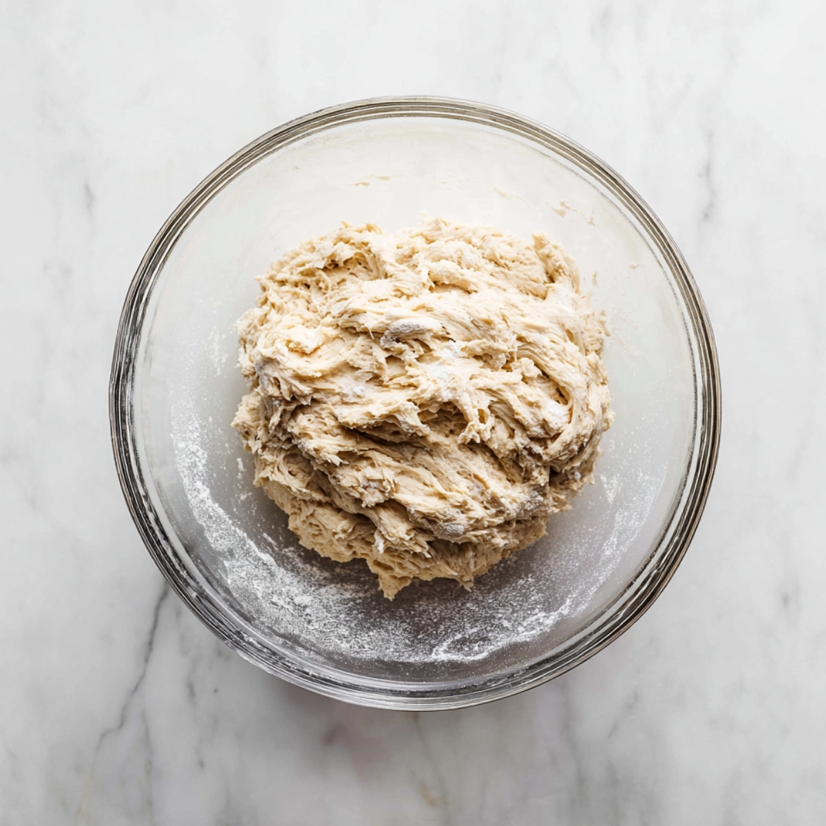 Homemade Artisan Bread Recipe 10 Freshly mixed artisan bread dough in a glass bowl on a marble countertop, ready for the first rise.