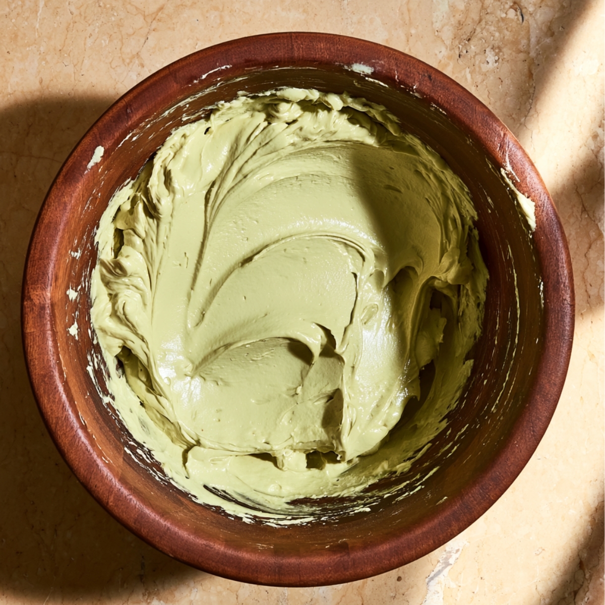 No Bake Dubai Chocolate Cheesecake 11 Creamy pistachio cheesecake filling whipped until smooth in a wooden mixing bowl, ready for a no-bake Dubai chocolate cheesecake.