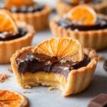 Chocolate Orange Tartlets with silky orange curd, rich dark chocolate ganache, and a dried orange slice garnish.