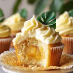 Pineapple Dole Whip Cupcakes with creamy frosting and sweet pineapple filling, topped with a tropical leaf garnish.