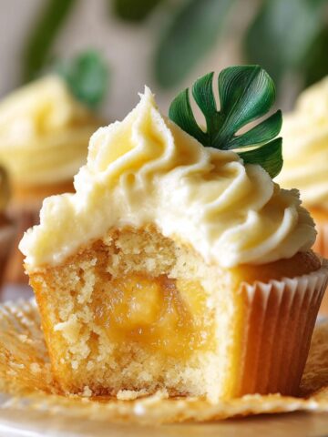 Easy Dole Whip Cupcakes Recipe 2 Pineapple Dole Whip Cupcakes with creamy frosting and sweet pineapple filling, topped with a tropical leaf garnish.