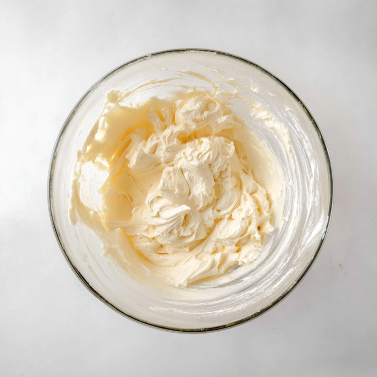 Easy Dole Whip Cupcakes Recipe 11 Creamy pineapple marshmallow buttercream frosting whipped until smooth in a clear glass mixing bowl.