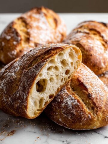 Homemade Artisan Bread Recipe 2 Homemade artisan bread with a crispy golden crust and soft airy crumb, sliced to reveal an open texture.