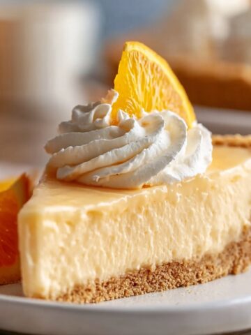 No Bake Jello Creamsicle Pie Recipe 2 Slice of creamy no-bake Jello Creamsicle Pie topped with whipped cream and a fresh orange slice on a graham cracker crust.