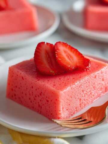 Easy Mexican Milk Jello Recipe 1 Creamy Mexican Milk Jello topped with fresh strawberry slices on a white plate, ready to enjoy.