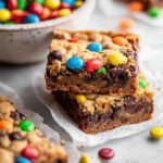Stacked Monster Cookie Brownies with a fudgy brownie base, chewy cookie topping, chocolate chips, and colorful M&M candies.