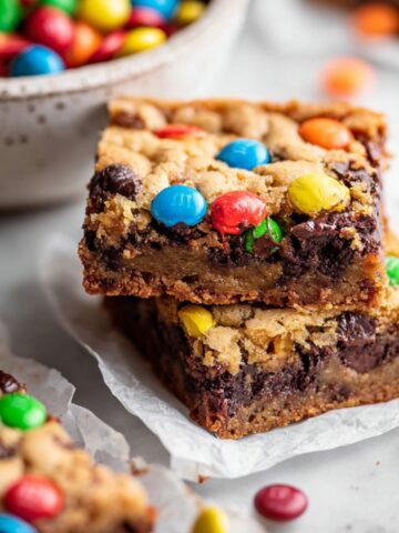 Easy Monster Cookie Brownies Recipe 1 Stacked Monster Cookie Brownies with a fudgy brownie base, chewy cookie topping, chocolate chips, and colorful M&M candies.