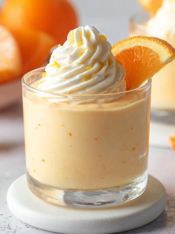 Easy Orange Mousse Cups Recipe 1 Creamy Orange Mousse Cups served in a glass dessert cup topped with whipped cream, orange slice, and fresh orange zest.