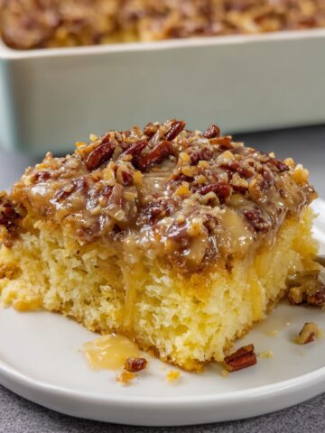 Best Texas Tornado Cake Recipe 2 Moist Texas Tornado Cake topped with warm coconut pecan frosting served on a white dessert plate.
