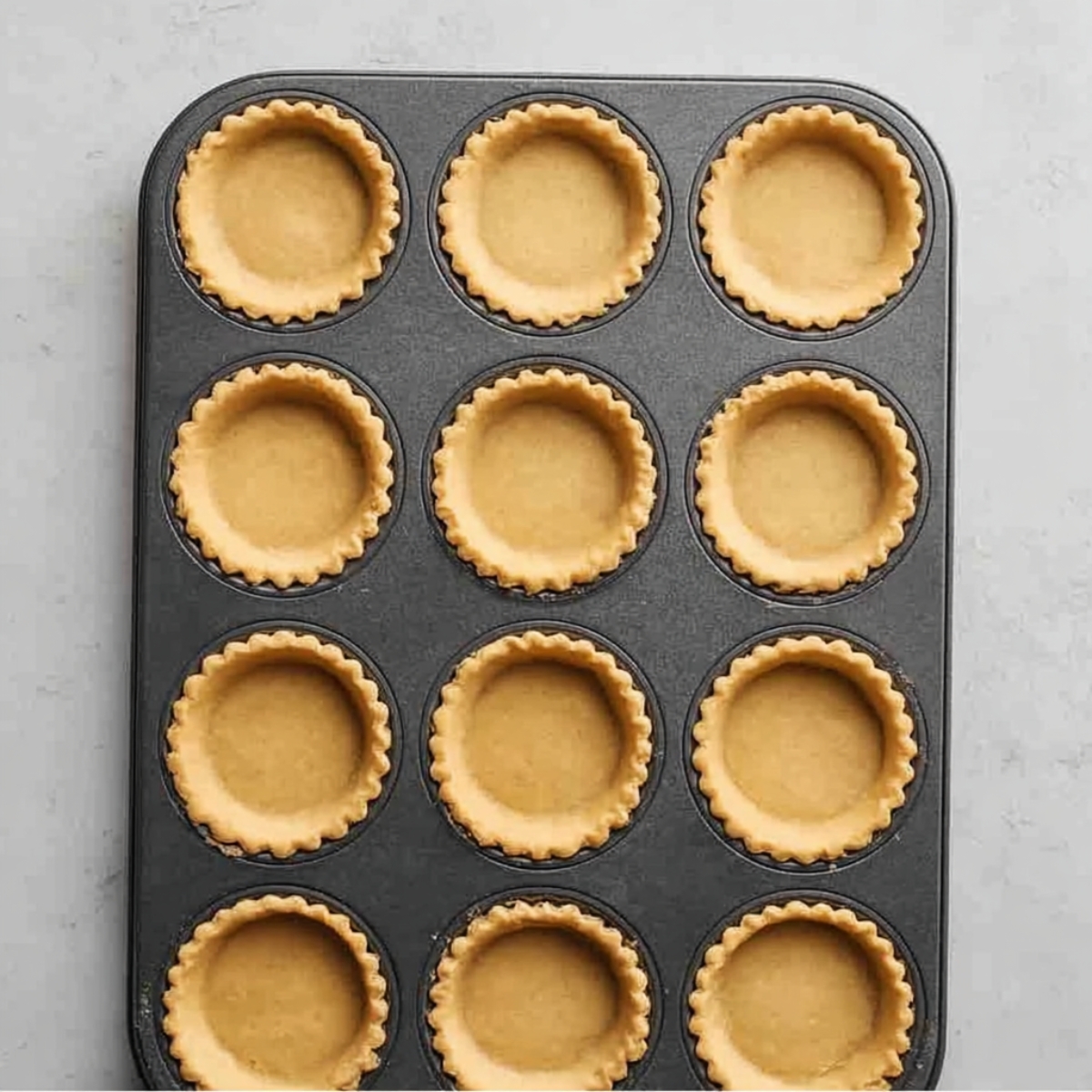 Easy Chocolate Orange Tartlets Recipe 10 Golden baked mini tart shells in a muffin pan ready to be filled with orange curd and chocolate ganache.