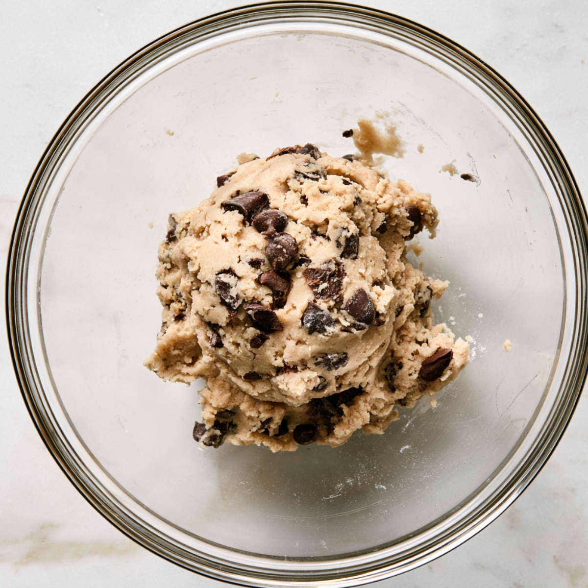 Easy Milk Chocolate Chip Cookies Recipe 10 Homemade chocolate chip cookie dough mixture with chocolate chunks in a glass mixing bowl
