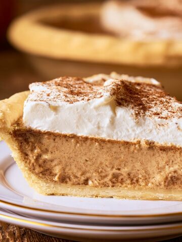 The Best Cinnamon Pie Recipe 2 Slice of creamy cinnamon pie topped with whipped cream and a dusting of ground cinnamon on a dessert plate.