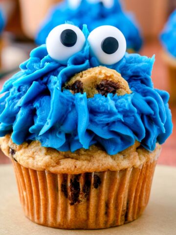 Easy Cookie Monster Cupcakes Recipe 2 Homemade Cookie Monster Cupcakes with bright blue frosting, candy eyes, and chocolate chip cookies on top.