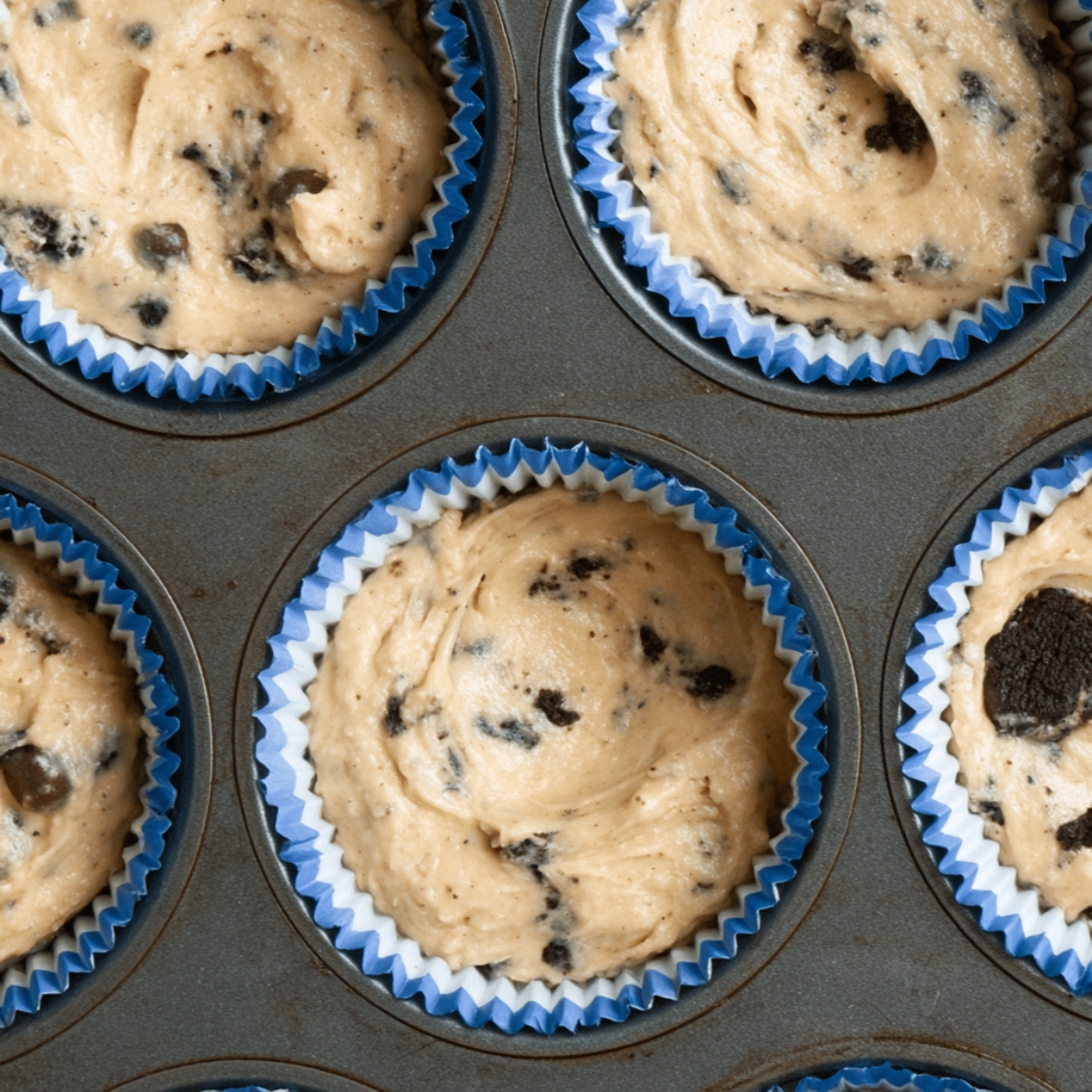 Easy Cookie Monster Cupcakes Recipe 11 Cookie Monster cupcake batter filled into blue and white cupcake liners in a muffin tray during baking preparation.
