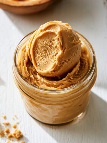 Best Edible Peanut Butter Cookie Dough 1 Jar of Edible Peanut Butter Cookie Dough topped with a perfectly scooped portion on a white wooden surface.