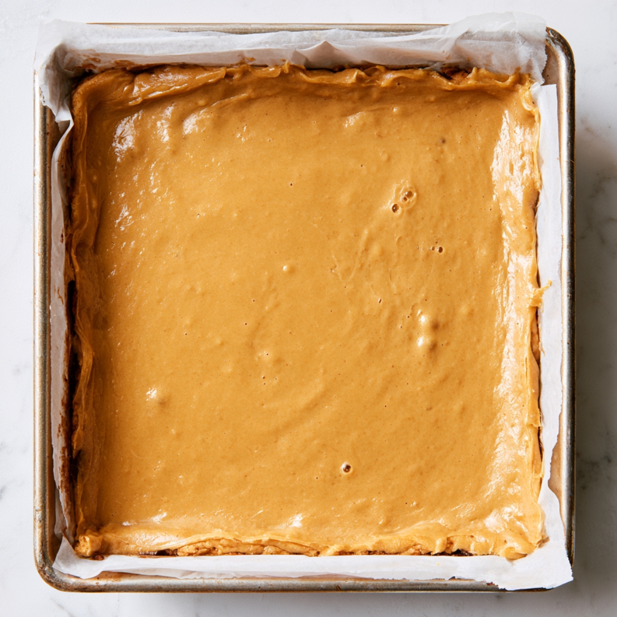 Easy Nutella Blondies Recipe 11 Smooth golden blondie batter spread evenly in a square baking pan for layering with Nutella.