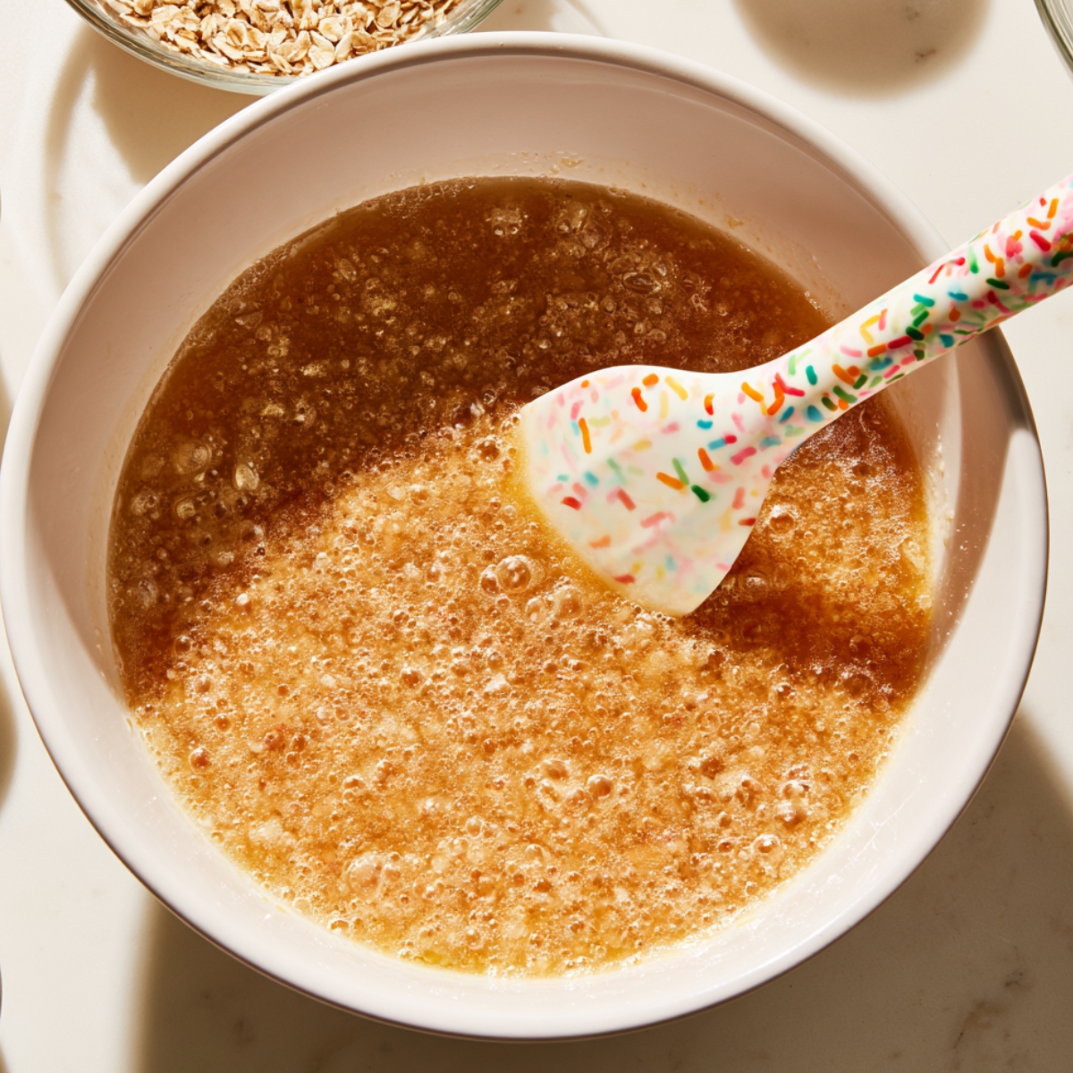 Easy Oatmeal Lace Cookies Recipe 10 Bubbling caramelized butter and sugar mixture being stirred with a silicone spatula.