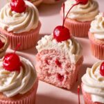 Homemade pink Maraschino Cherry Cupcakes topped with vanilla buttercream and glossy red cherries.