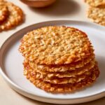Stack of thin, crisp golden Oatmeal Lace Cookies on a white plate.