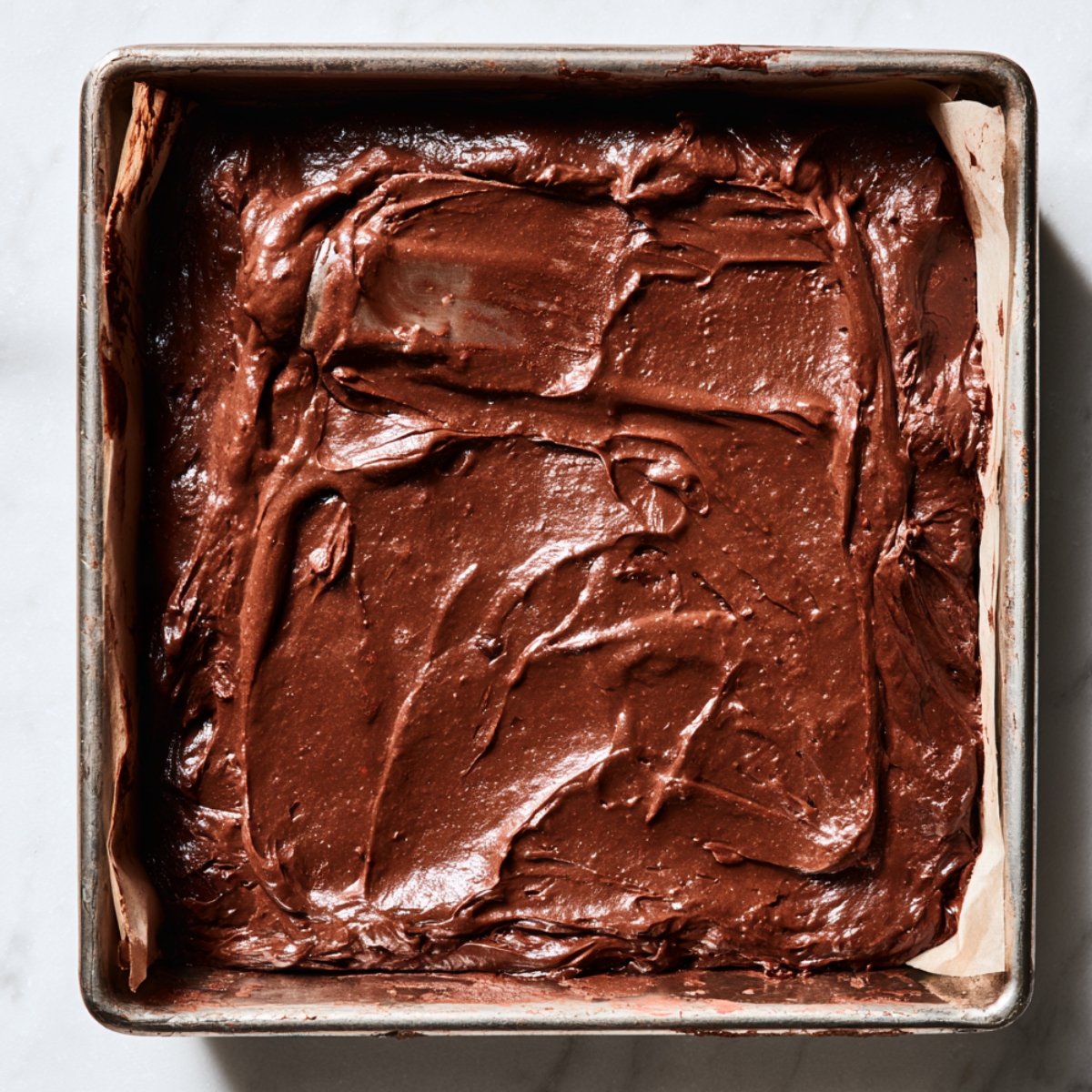 The Best Espresso Brownies Recipe 11 Thick, glossy espresso brownie batter evenly spread in a parchment-lined square baking pan, ready to bake with a smooth, rich chocolate surface.